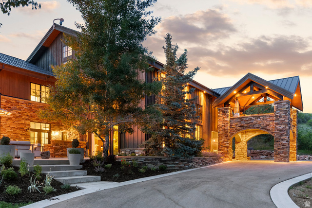 5971 Maple Ridge Trail Oakley, UT 84055 - Photo 37 of 43 Expansive residence featuring a stone and vertical wood-plank facade, a porte-cochère with stone archway, and a covered entry with exposed beam ceiling