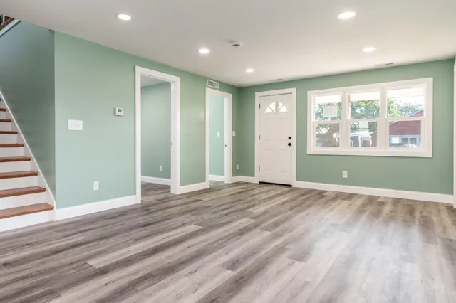 an empty room with wooden floor and windows