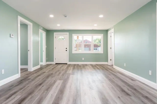 an empty room with wooden floor and windows