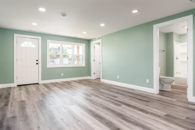 an empty room with wooden floor and windows