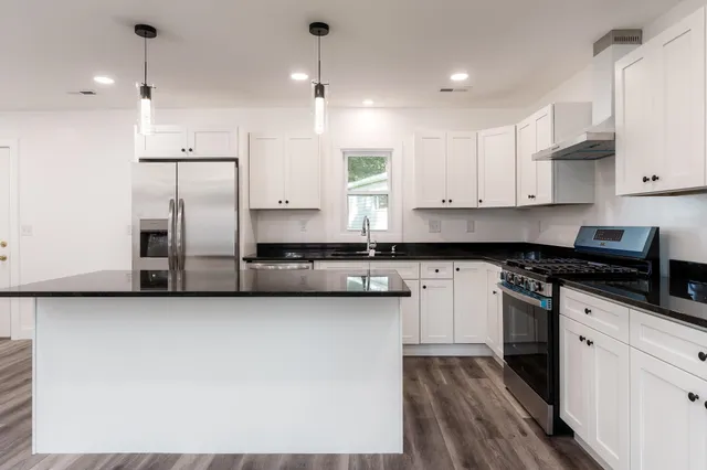 a kitchen with stainless steel appliances granite countertop a stove a sink and a refrigerator