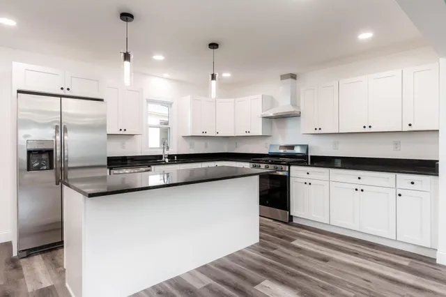 a kitchen with stainless steel appliances granite countertop a sink a stove and refrigerator