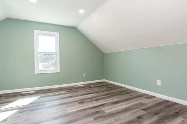 an empty room with wooden floor and window