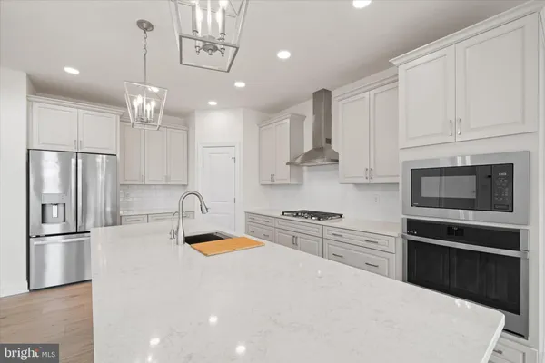 a kitchen with granite countertop a refrigerator oven a sink and cabinets
