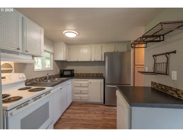 a kitchen with granite countertop a refrigerator stove top oven and sink