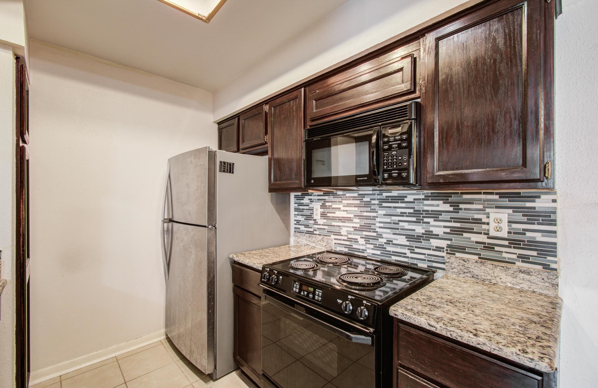 8299 Cambridge Street, Unit 1706 Houston, TX 77054 - Photo 11 of 26 a kitchen with granite countertop stainless steel appliances and wooden cabinets