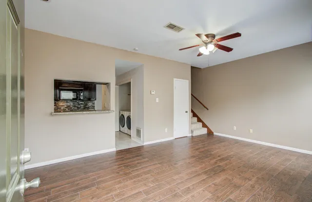 a view of a hallway with wooden floor and a ceiling fan