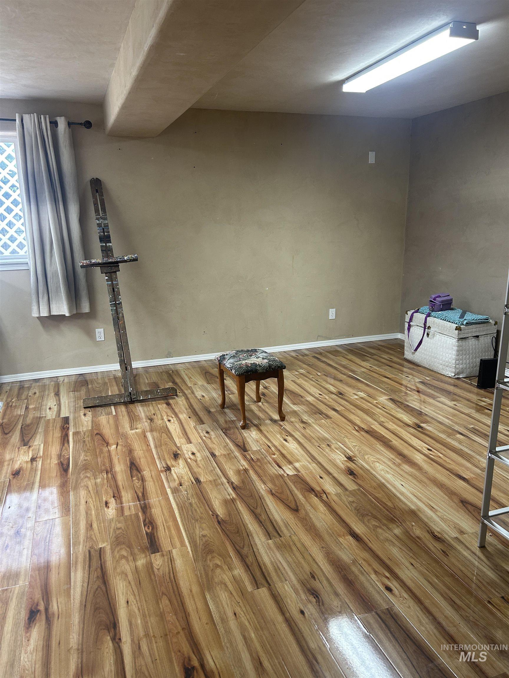 1444 East Doberman Street Meridian, ID 83642 - Photo 11 of 31 Spacious room with wood-finish flooring, neutral-toned walls, and a recessed ceiling beam