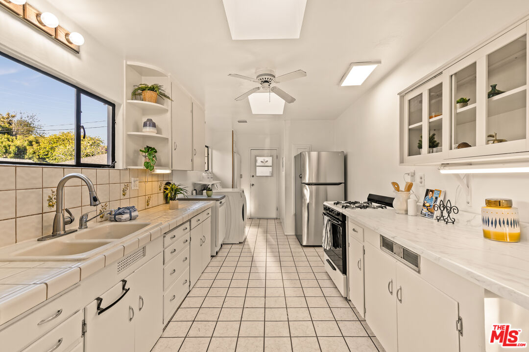 1100 Victoria Avenue Venice, CA 90291 - Photo 12 of 30 a large white kitchen with a sink dishwasher a stove and white cabinets with wooden floor
