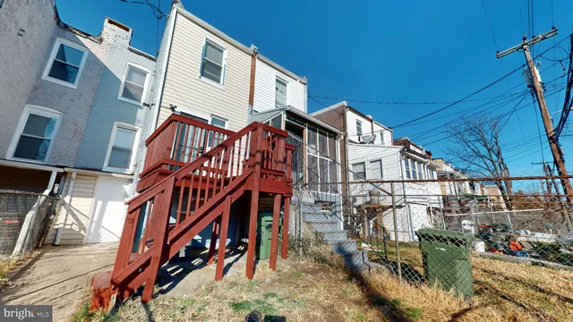 a view of a house with a small yard and wooden deck
