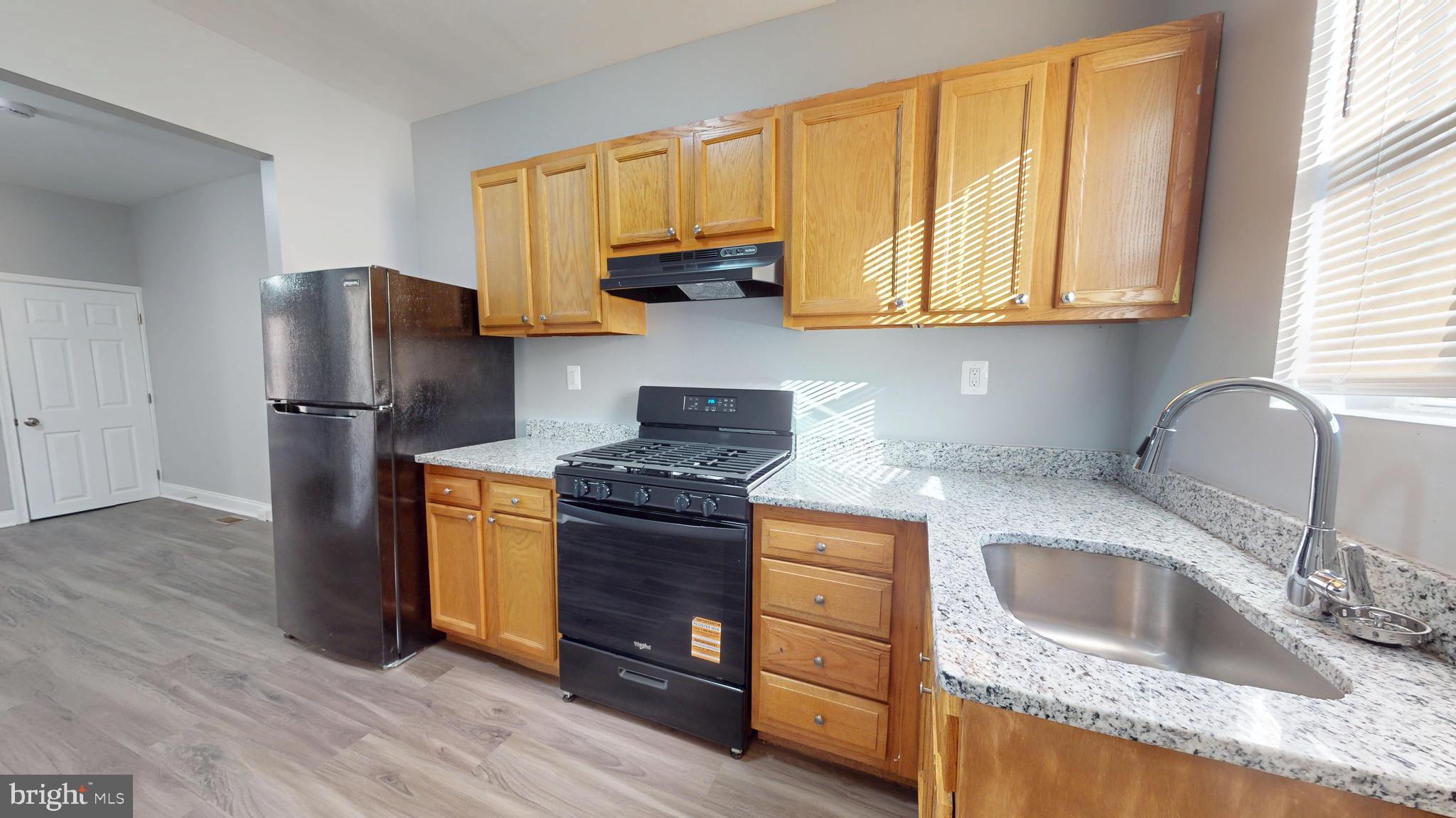 2615 East Chase Street Baltimore, MD 21213 - Photo 8 of 17 a kitchen with stainless steel appliances granite countertop a sink stove and refrigerator