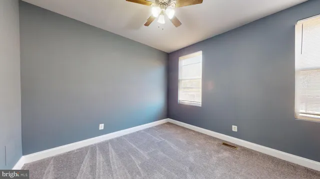 an empty room with windows and fan