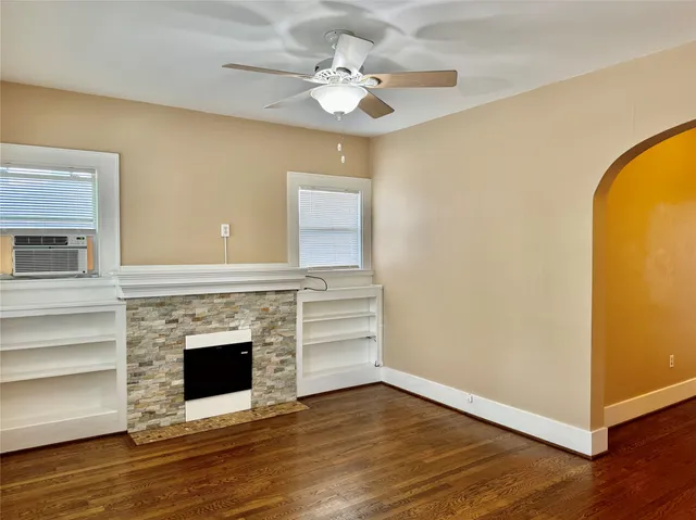 a view of a livingroom with a fireplace a ceiling fan and wooden floor