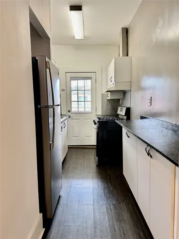 a kitchen with a refrigerator a sink and wooden floor