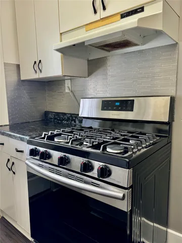 a stove sitting inside of a kitchen with white cabinets