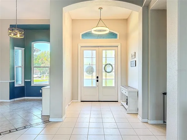 a dining room with stainless steel appliances kitchen island granite countertop a table chairs and a chandelier