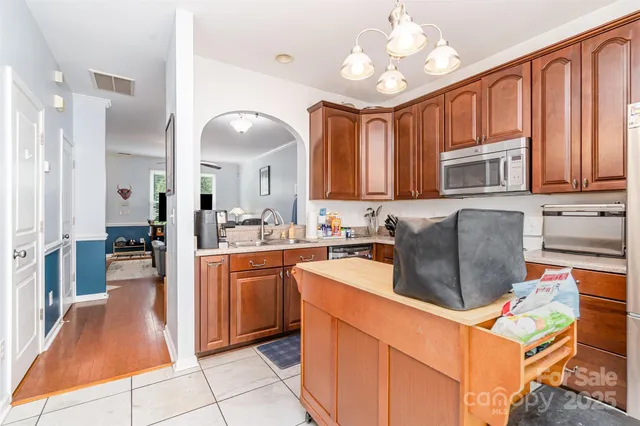 a kitchen with stainless steel appliances granite countertop a refrigerator a stove top oven and a sink with cabinets