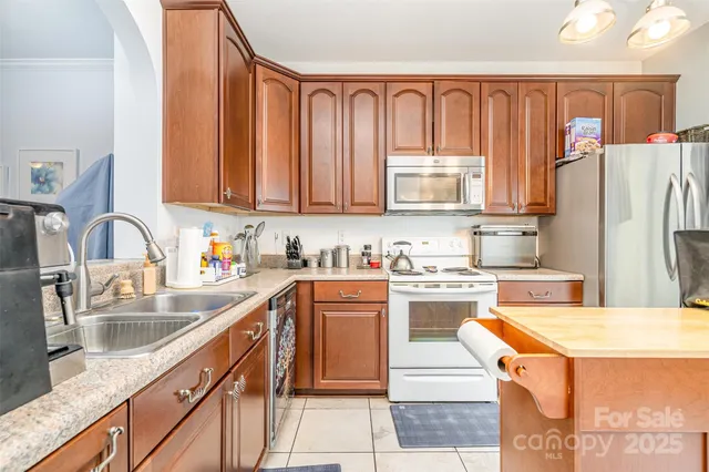 a kitchen with stainless steel appliances granite countertop a stove top oven a sink dishwasher and a refrigerator
