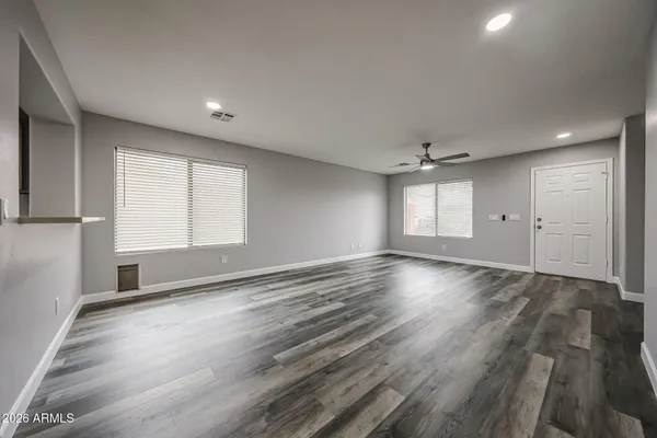 an empty room with wooden floor and windows