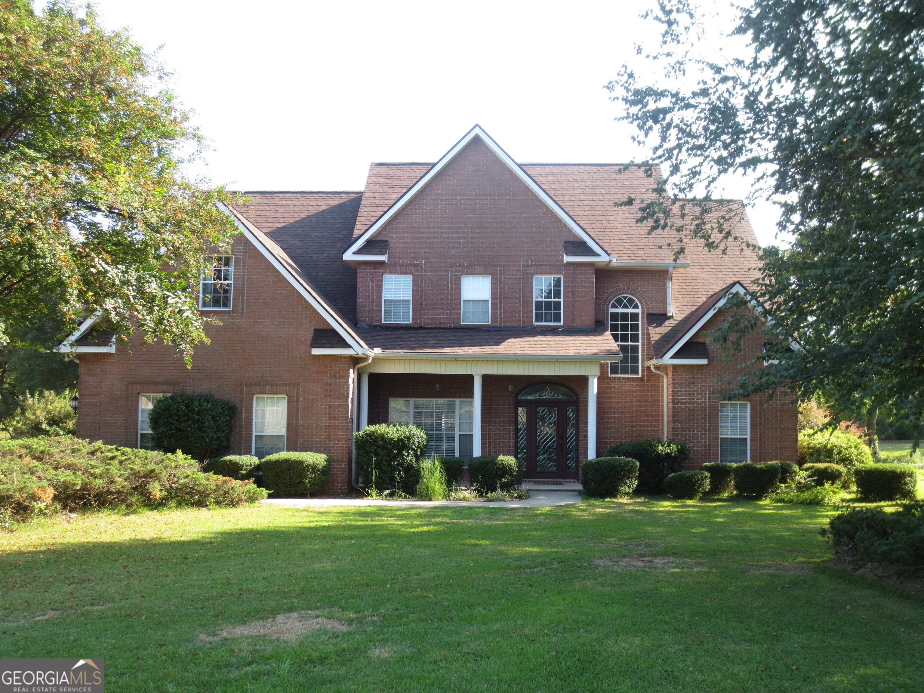 a front view of a house with a yard and trees