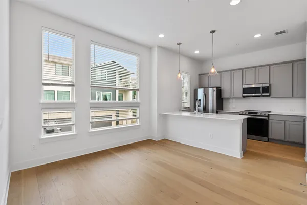 a large kitchen with stainless steel appliances granite countertop a stove a sink dishwasher a microwave oven with cabinets and wooden floor