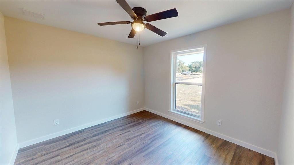 1110 Mill Run Road Athens, TX 75751 - Photo 18 of 32 an empty room with wooden floor ceiling fan and windows