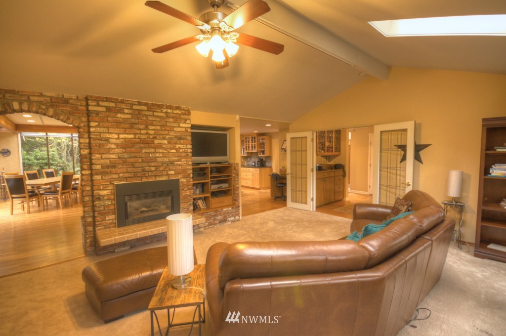 509 Bayside Road Bellingham, WA 98225 - Photo 6 of 17 a living room with couches a fireplace and a dining table with wooden floor
