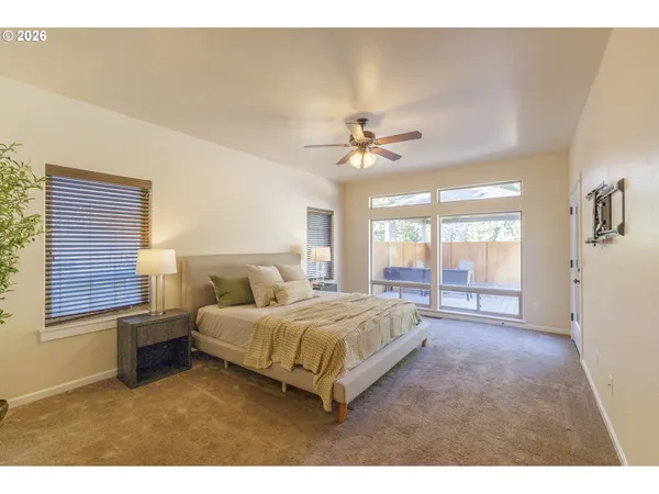 a spacious bedroom with a bed a chandelier and a large window