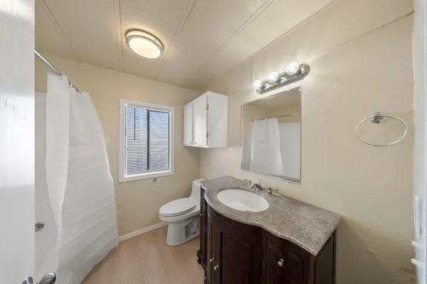 a bathroom with a granite countertop sink toilet and mirror