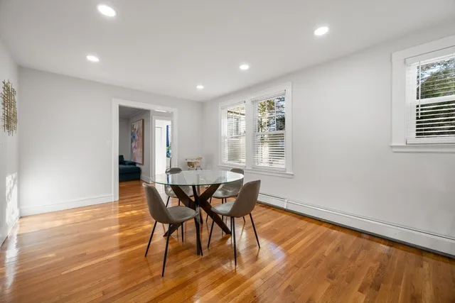 a large white kitchen with furniture a refrigerator a stove a sink a dining table and chairs with wooden floor