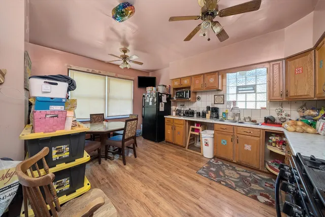 a kitchen with stainless steel appliances kitchen island granite countertop a sink dishwasher a stove a dining table and chairs with wooden floor