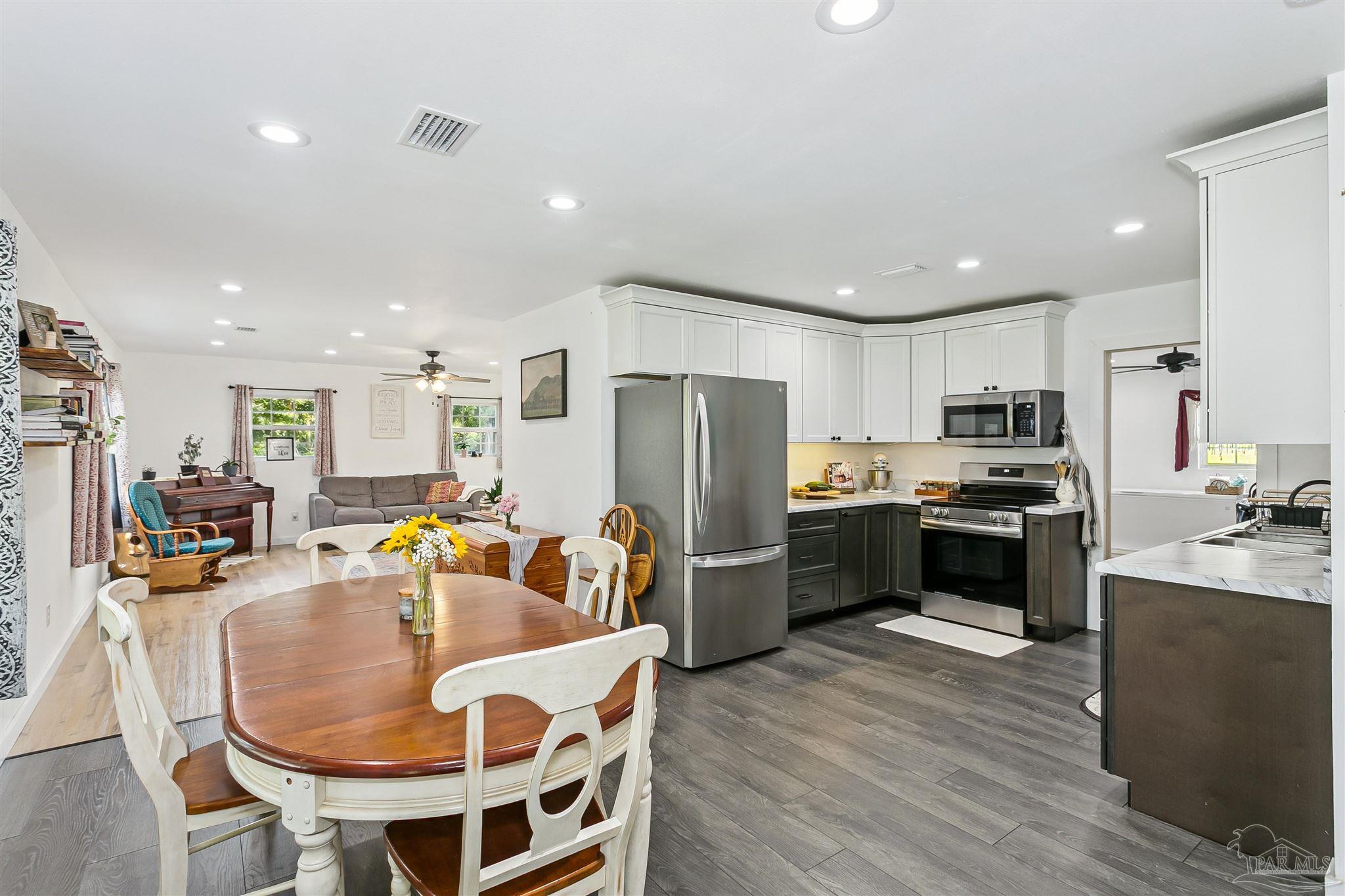 1095 River Annex Road Cantonment, FL 32533 - Photo 7 of 32 a kitchen with stainless steel appliances kitchen island granite countertop a refrigerator a stove a sink a dining table and chairs
