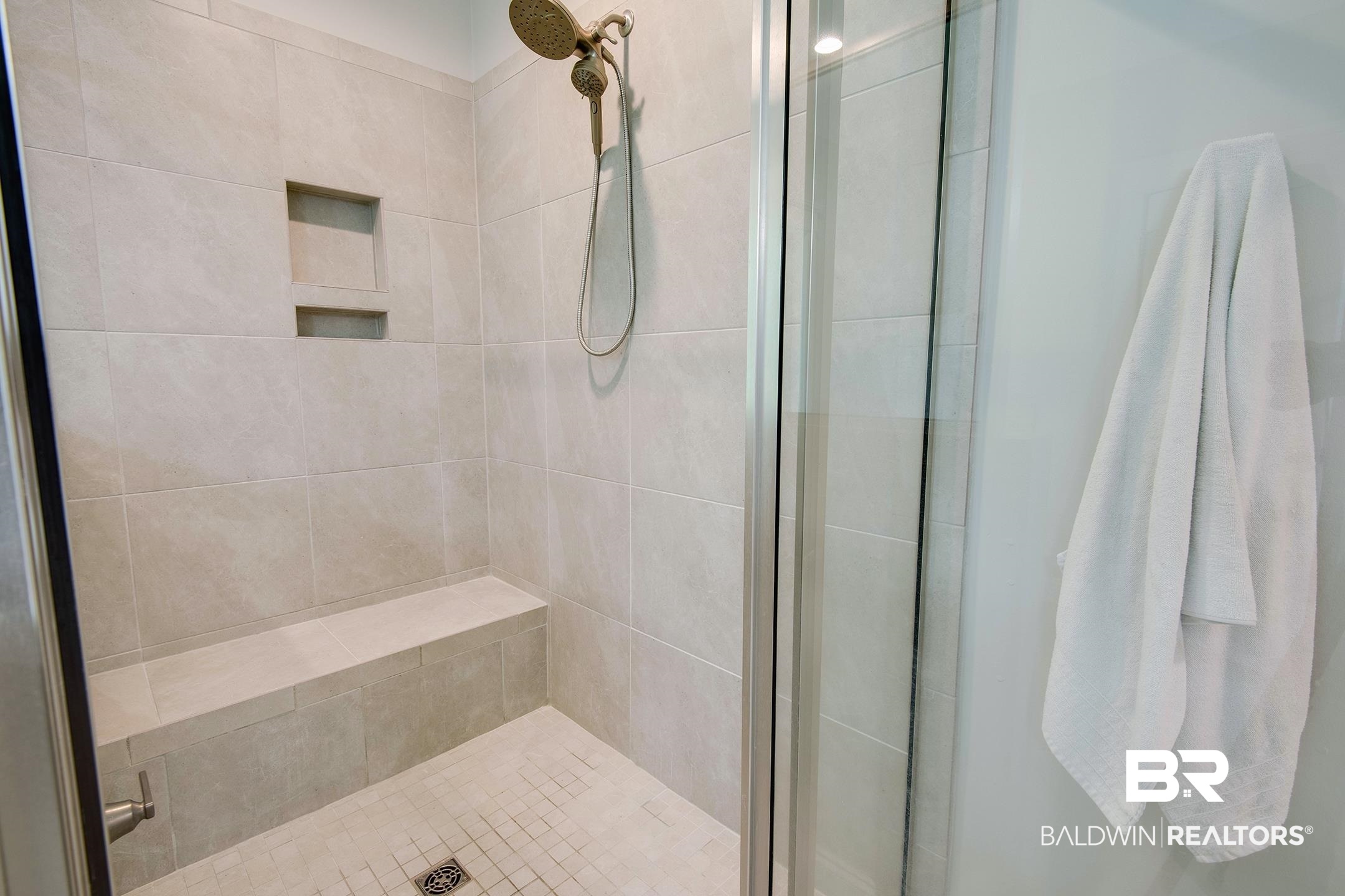 18754 Treasure Oaks Road Gulf Shores, AL 36542 - Photo 18 of 53 Tiled shower with a built-in bench, recessed niche, square floor tiles, and a glass enclosure