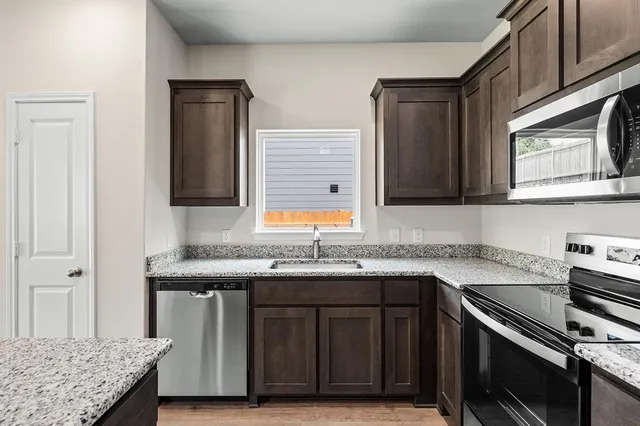 a kitchen with stainless steel appliances granite countertop a sink stove and cabinets