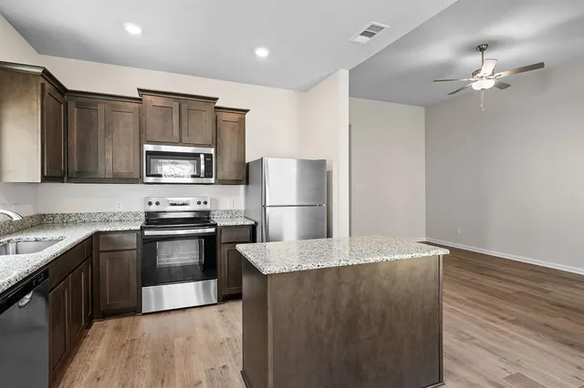 a kitchen with granite countertop a refrigerator and a stove top oven
