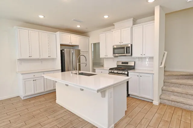 a kitchen with kitchen island white cabinets and stainless steel appliances