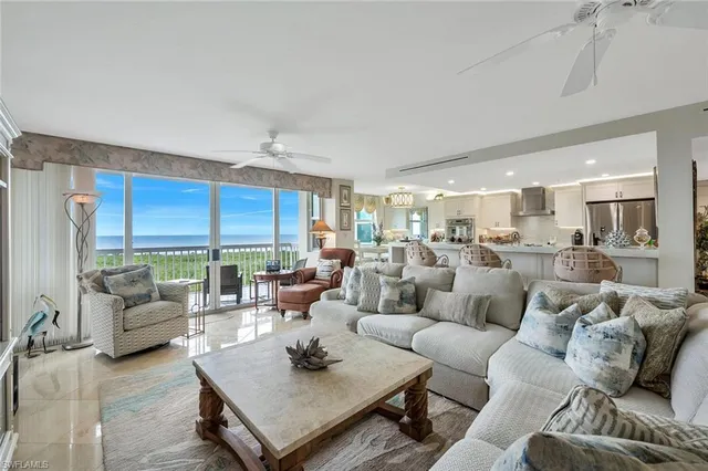 a living room with furniture kitchen view and a large window