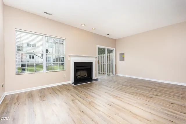 a view of empty room with wooden floor and fireplace