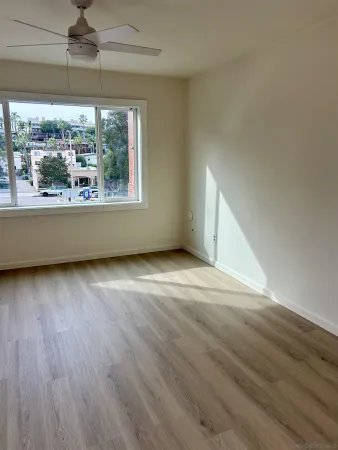 an empty room with wooden floor and windows