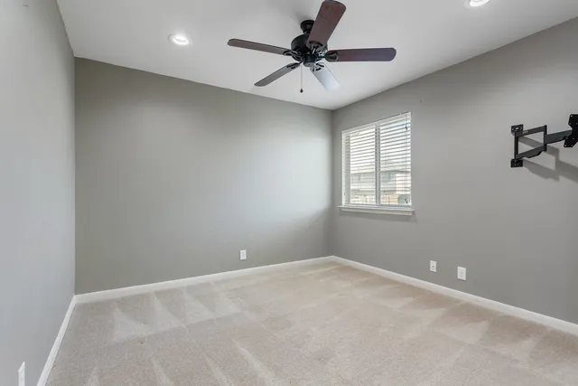 an empty room with a chandelier fan and windows