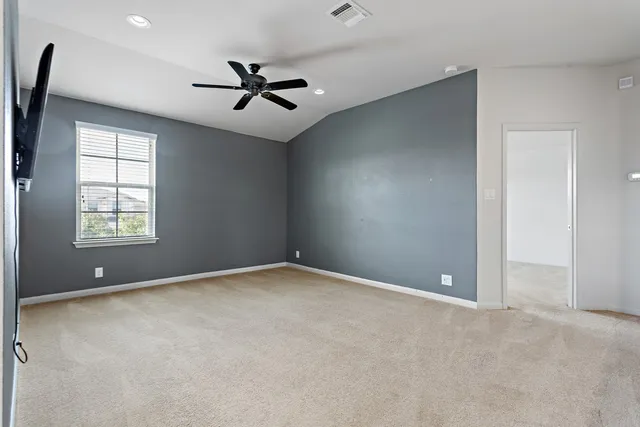 an empty room with windows and ceiling fan
