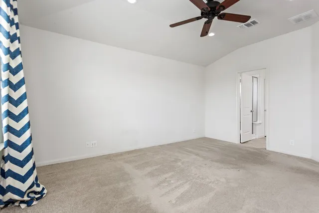 an empty room with a ceiling fan and carpet