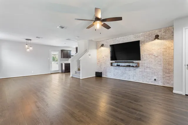 a view of a livingroom with wooden floor a ceiling fan and a window