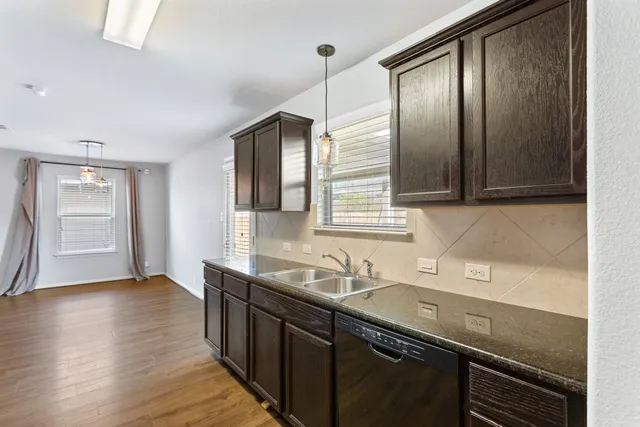 a kitchen with granite countertop a sink cabinets and wooden floor