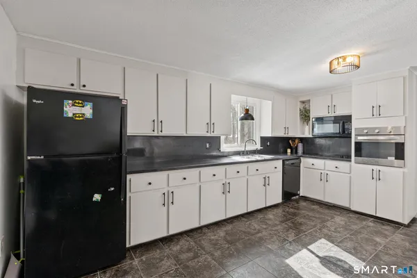 a kitchen with granite countertop white cabinets and refrigerator