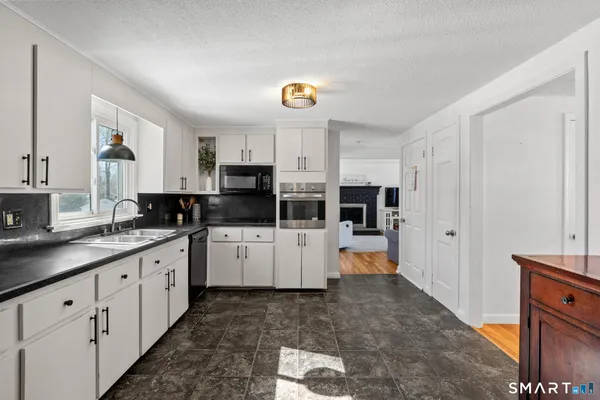 a large white kitchen with cabinets a sink and appliances
