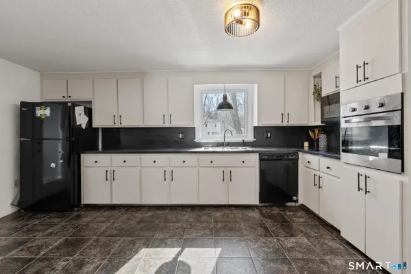 a kitchen with granite countertop a refrigerator a stove a microwave and cabinets
