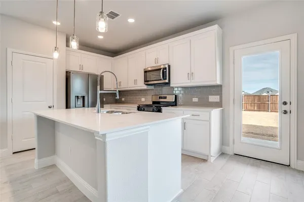 a kitchen with kitchen island a sink stainless steel appliances and cabinets