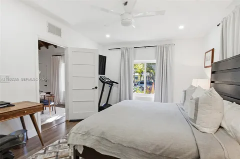 a bedroom with a bed next to a large window with wooden floor