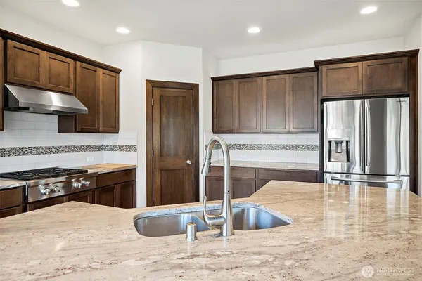 a kitchen with stainless steel appliances granite countertop a stove and a refrigerator